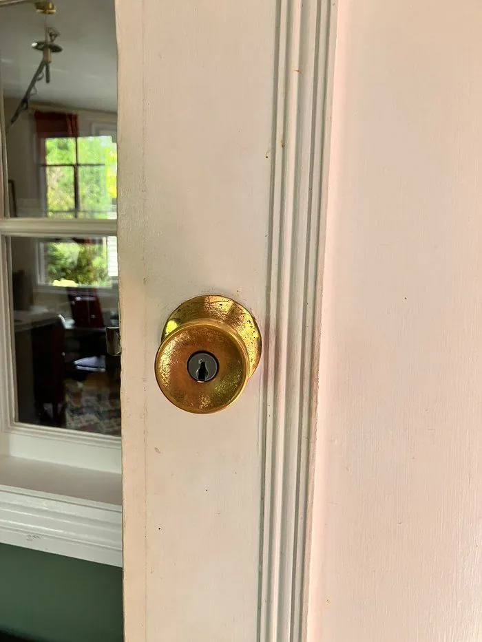 Old worn brass door knob, unused for years after the original keys were lost, on a home in Witney