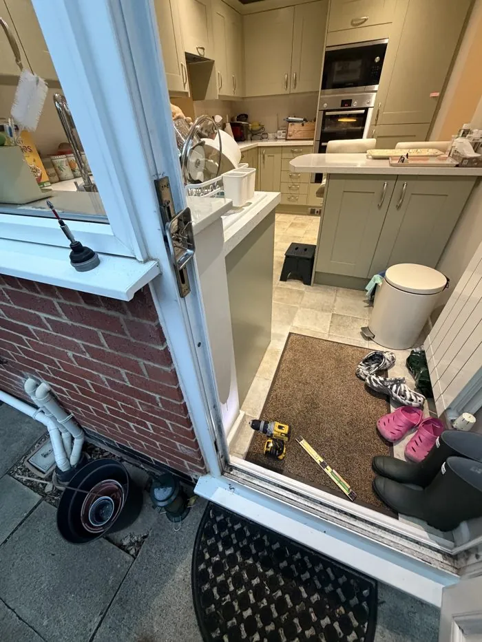 uPVC back door open during a door realignment in Bloxham, with the multi-point lock and spirit level in view