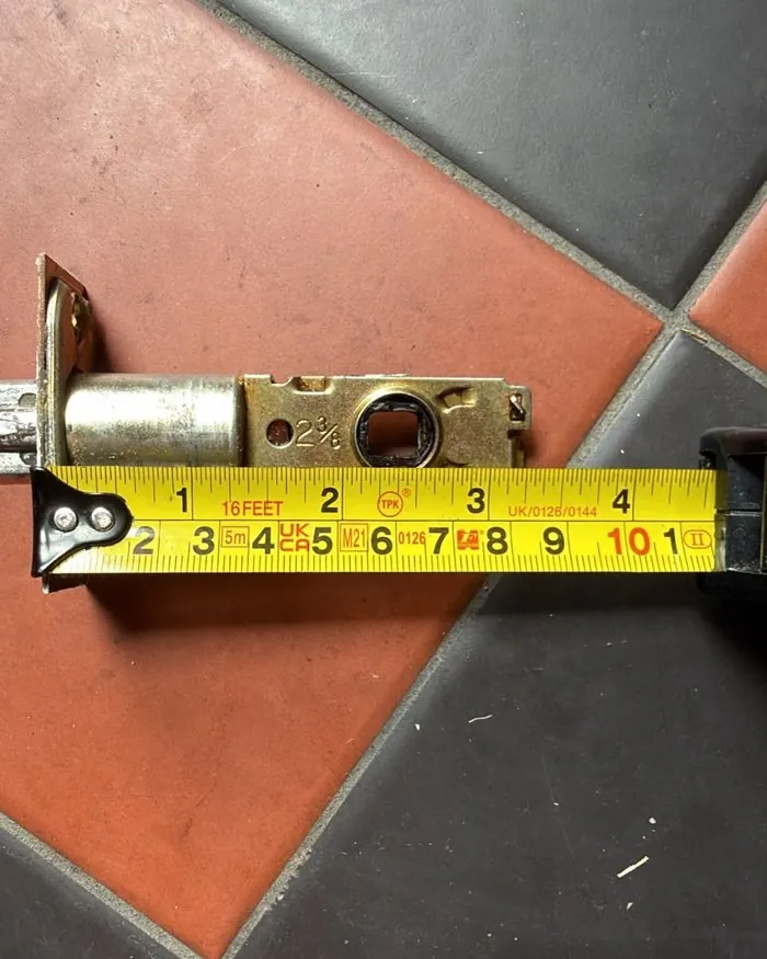 Faulty tubular door latch being measured for backset during a repair in Hook Norton
